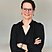 A brunette women with glasses in a black blouse is smiling into the camera