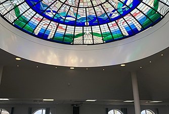 A circular stained-glass dome in blue and green spans a large interior space.