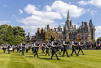 Boarding school parade on green lawn in front of castle building