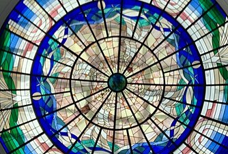 Circular stained-glass window with a geometric pattern in blue, green and purple