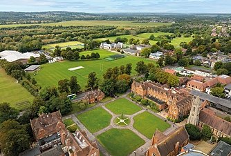 Aerial view of an expansive school campus with sports fields, academic buildings, and tree-lined paths.
