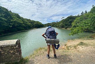 A Ryde School pupil with backpack looking at a lake