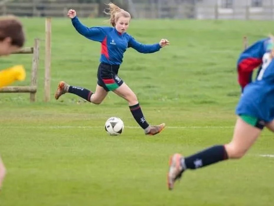 Girls playing football outside in their jerseys