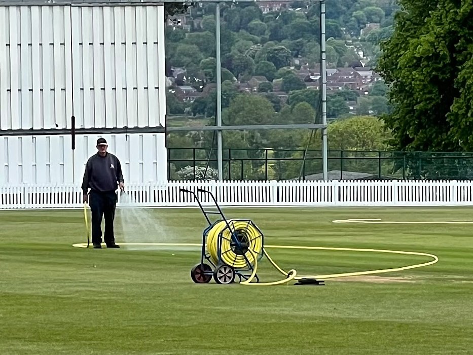 A gardener is watering the grass of the school's sports fields