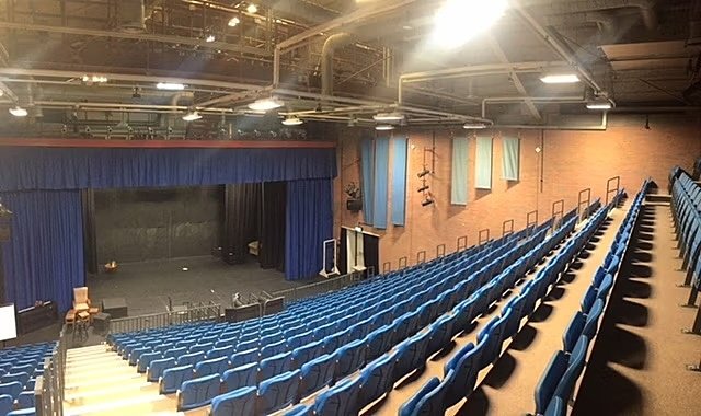 View from the top rows: theatre with blue curtain and black stalls