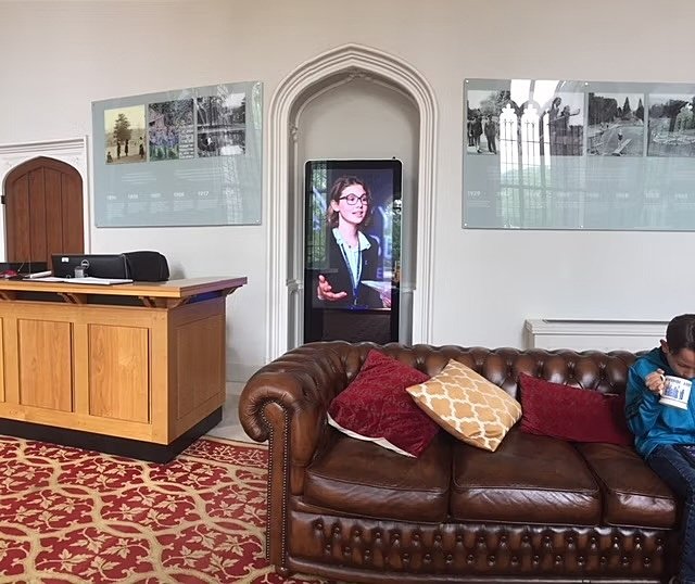 Brown leather sofa on red and beige carpet, reception desk