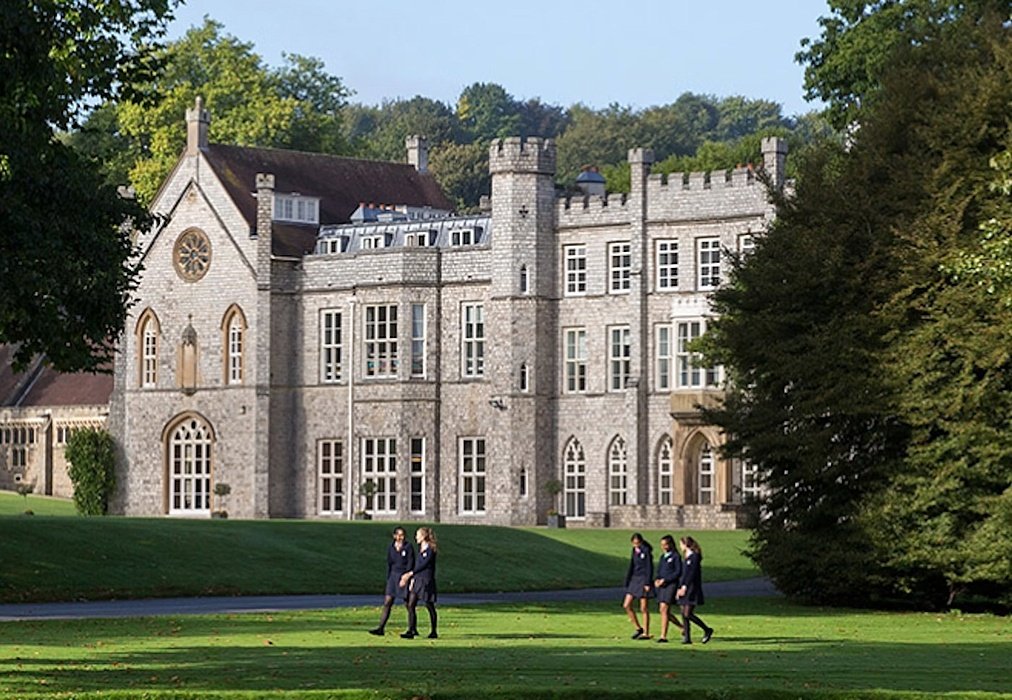 Old stately estate with a green lawn and students
