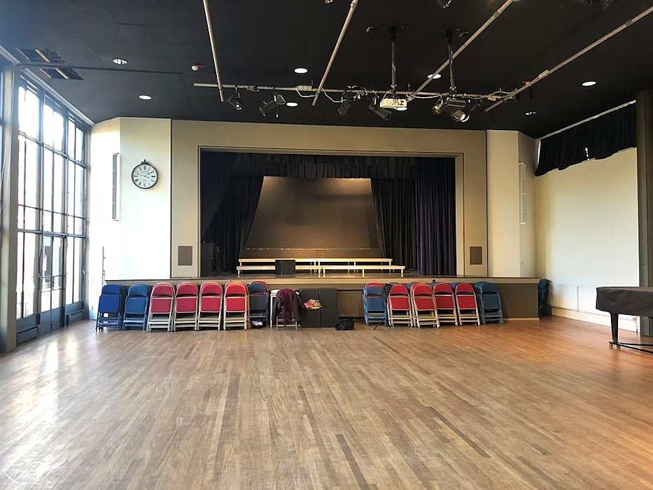 a performance hall with red and blue chairs infront of the stage