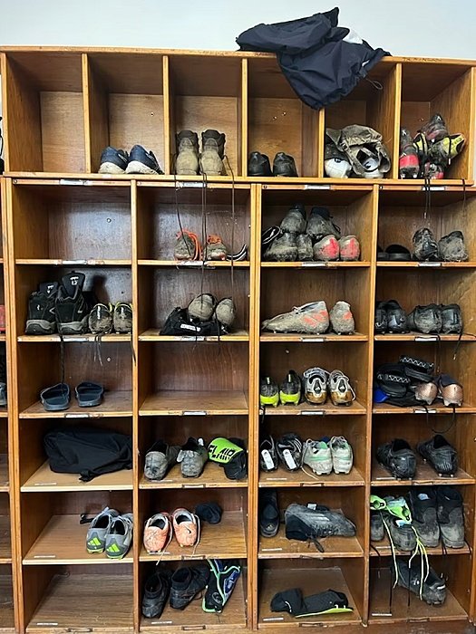 A shelf full of shoes and muddy football boots