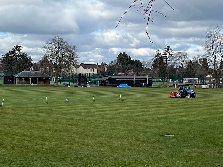 a Sportsfield with a blue tractor working on it