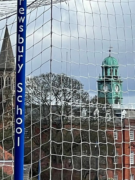 view through a football net onto the school’s tower rising in the background