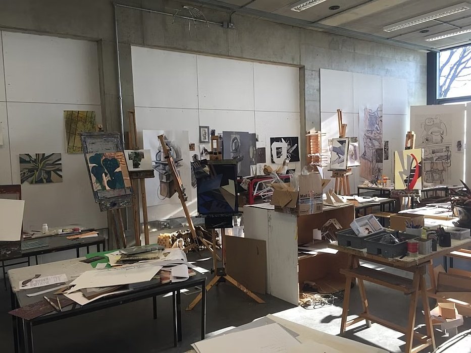 a busy art studio in a school with easels and pieces of art