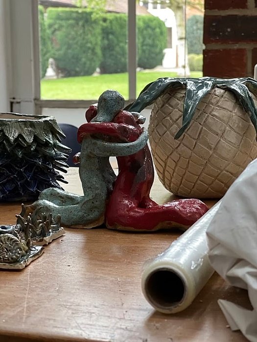 a hugging two piece clay sculpture in-between other clay sculptures