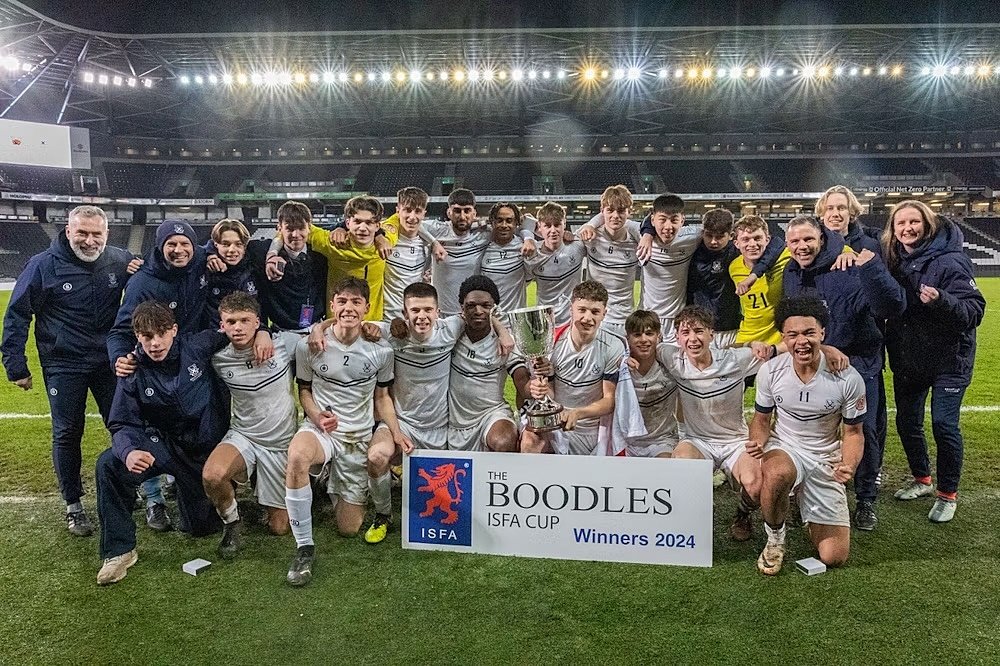 School football team celebrating with a trophy after winning the Boodles ISFA Cup 2024.
