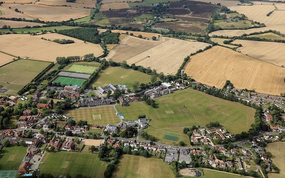 Aerial view of a large countryside campus with sports fields, buildings, and farmland.