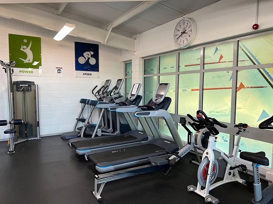 Modern gym with treadmills, exercise bikes, and motivational wall graphics.