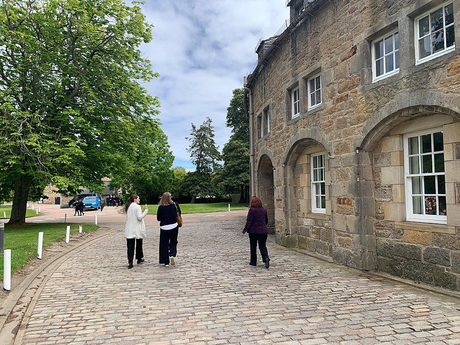 People walking across campus between historic buildings. Student life.