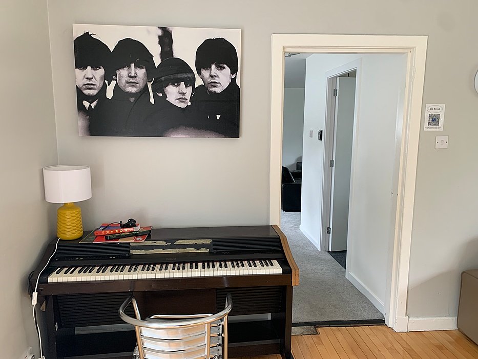 Boarding house common room with piano and seating area.