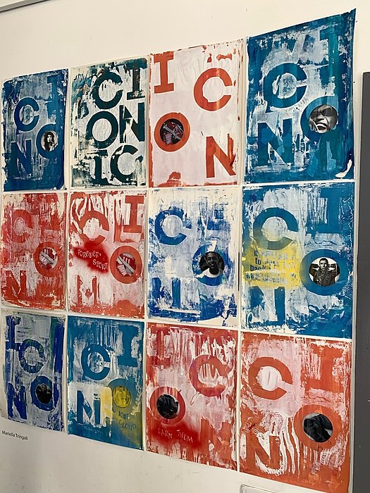 A wall is covered with square prints in red, blue and white, featuring letters and patterns.