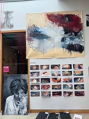 Mixed-media artworks and student sketches pinned to a wall