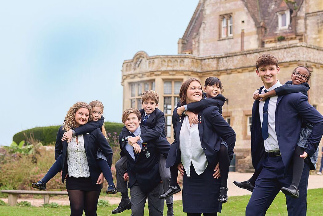 Happy students in uniform smiling outside school building.
