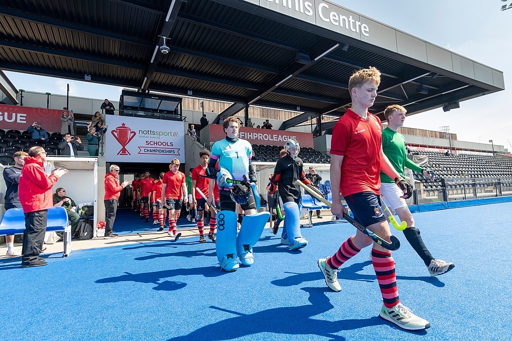 A hockey team is entering their hockey pitch for a match