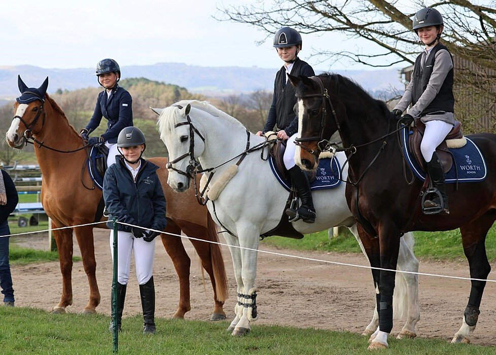 The Equestrian Team at Worth School with three happy students on their horses