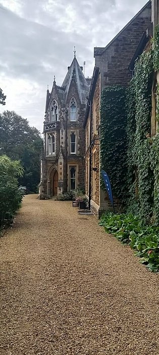 A beautiful old boarding house with a pointed roof and walls overgrown with ivy