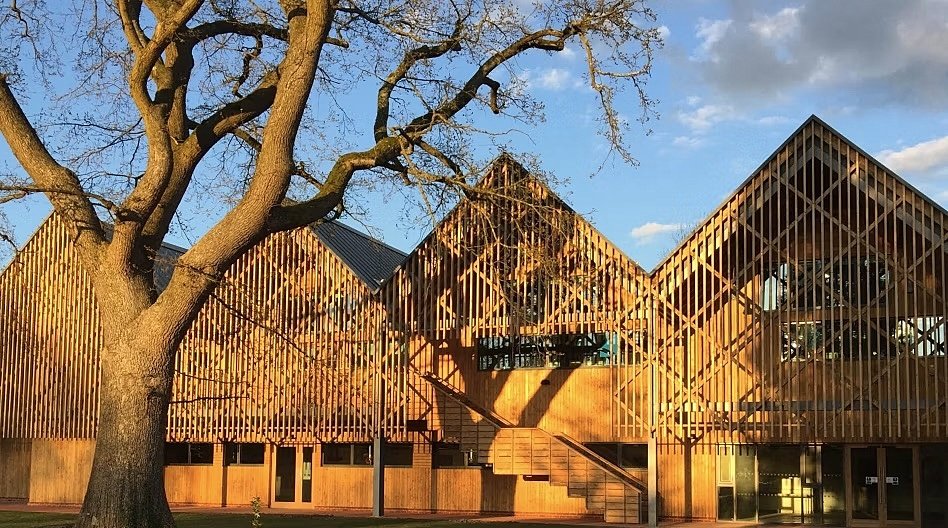 Wooden houses with four roofs and a wooden trellis structure, blue sky and a winter tree infront