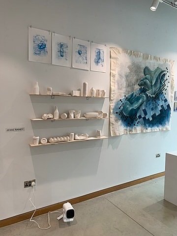 Ceramic bowls and abstract paintings in a minimalist gallery