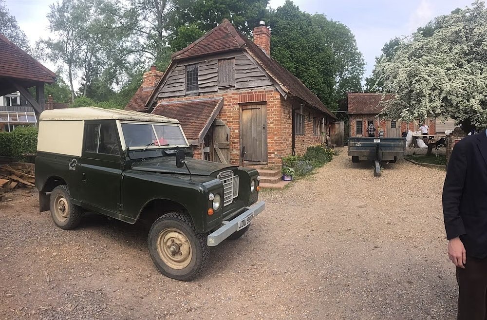 Old rangerover infront of outhouse, blossoming tree on the right