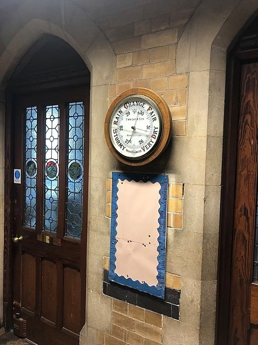 An antique barometer mounted on a stone wall