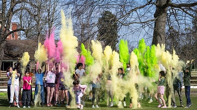 Students celebrating outdoors with colorful powder clouds