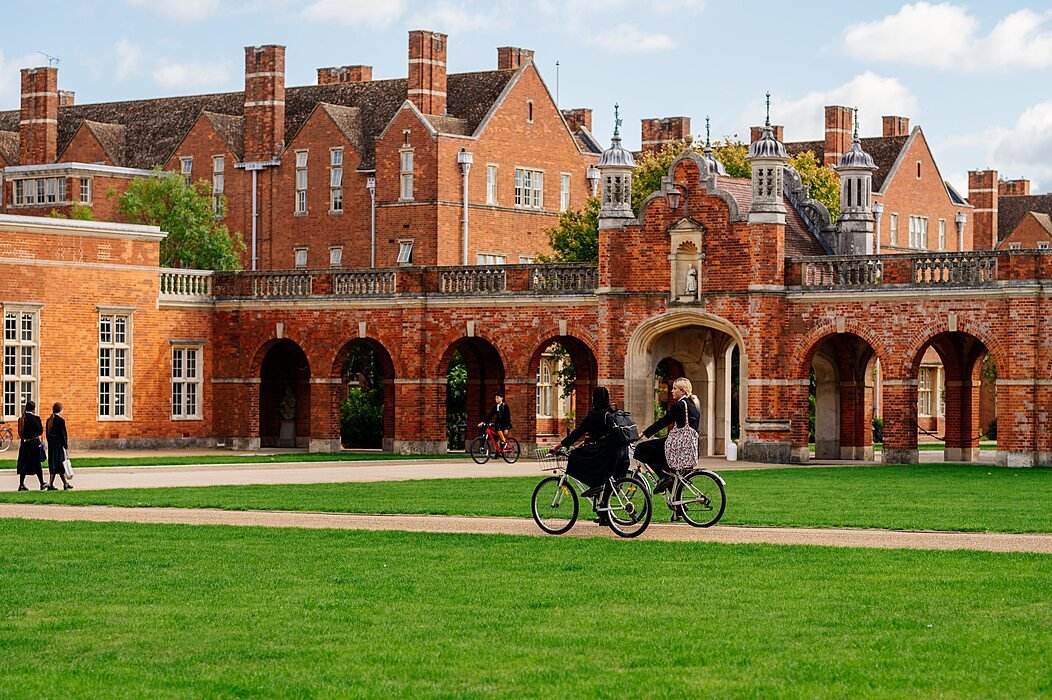 Historic red-brick British boarding school with students cycling