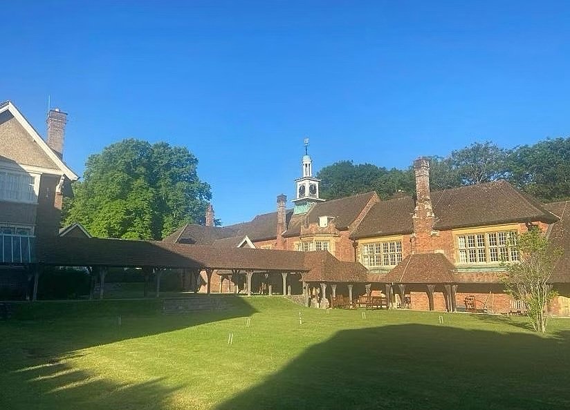 A courtyard of a traditional brick building with wooden beams and a small tower under a clear blue sky.