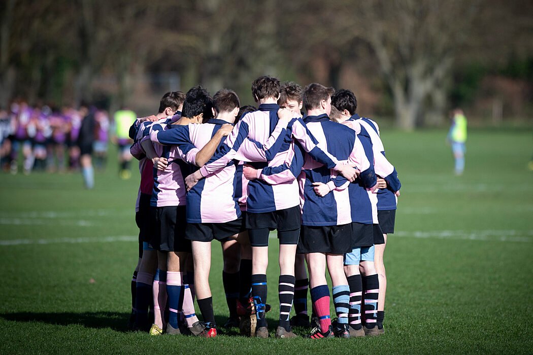 School rugby team huddling before match on field