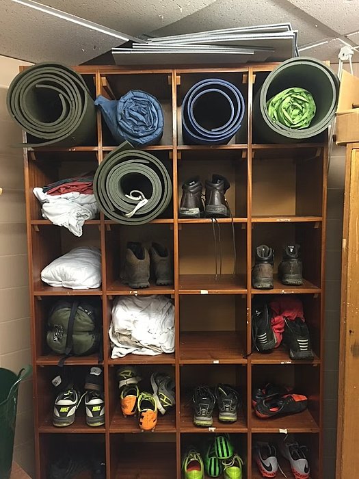 Shelf filled with mountain boots, and rolled-up camping mats