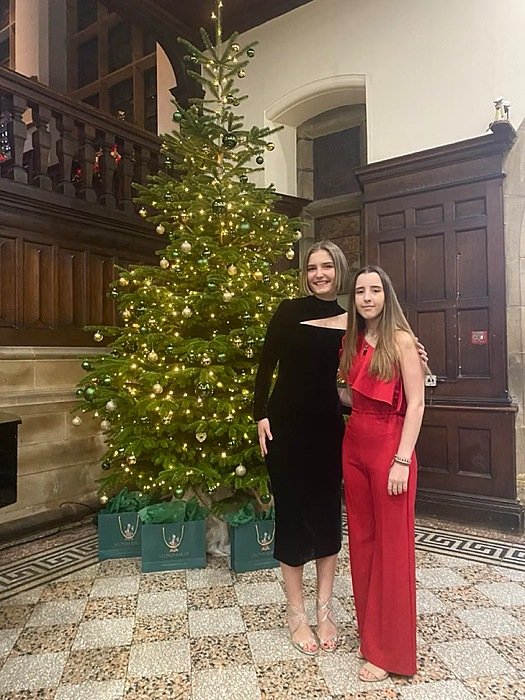Two girls in evening dresses in front of a Christmas tree