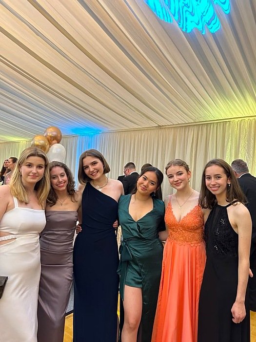 Six girls in evening gowns, smiling into the camera
