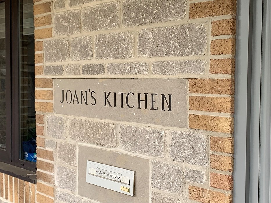 "Joan’s Kitchen” sign on a brick wall at an English boarding school