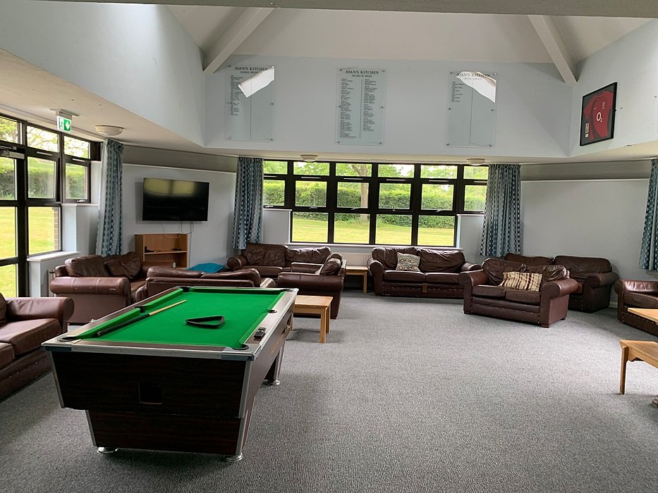 Boarding school common room with pool table, sofas and bright windows — a relaxed social space for students in England.