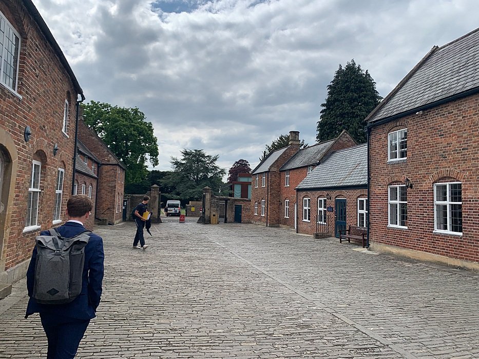 Cobbled driveway and red-brick boarding houses at a historic British school campus.