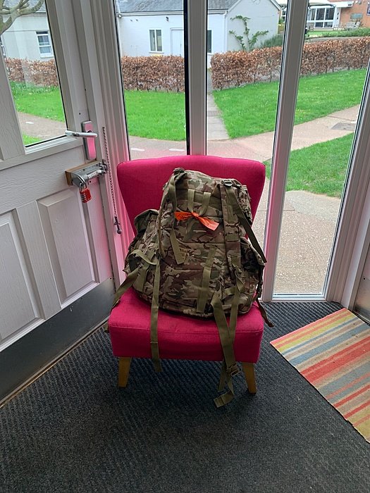 Army Backpack on a pink armchair in a boarding house entrance area