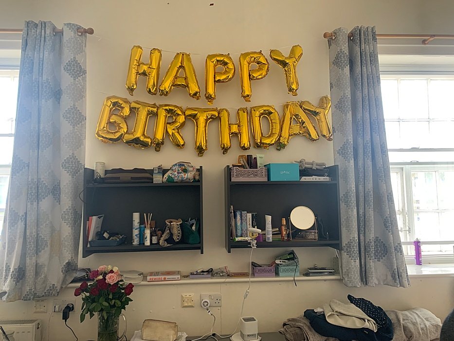 Gold “Happy Birthday” balloons above a desk in a boarding room