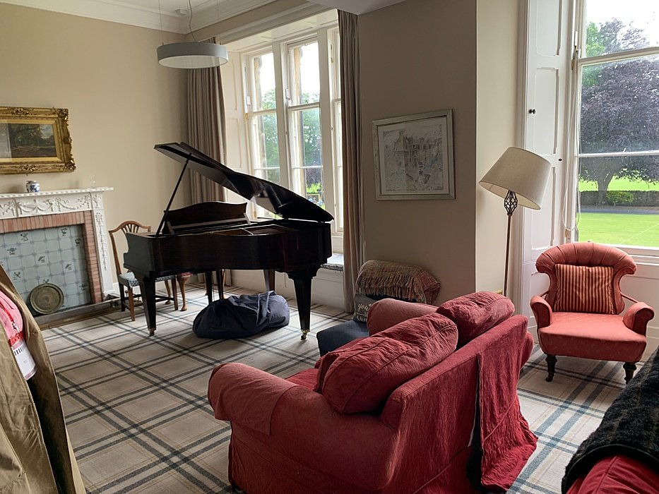 Music room with grand piano and seating area.