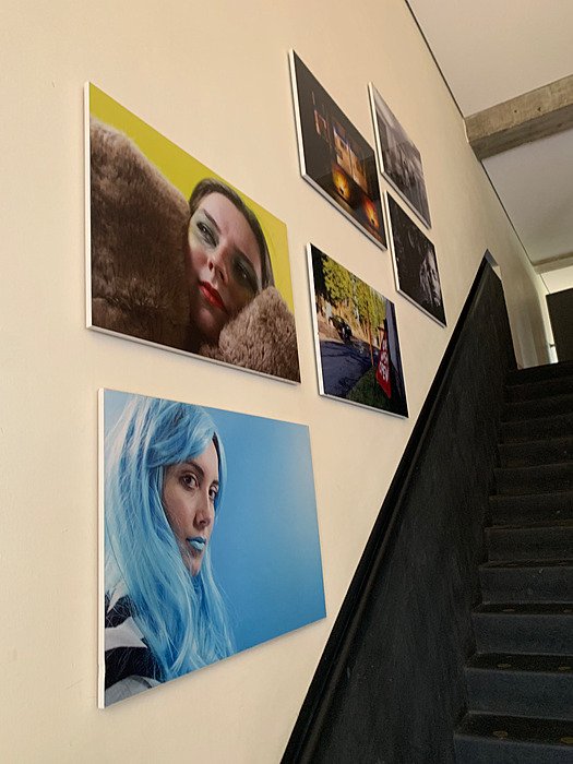 Large portrait photographs and other artwork displayed in the school stairwell.