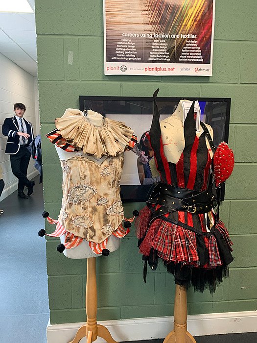 Student-designed costumes displayed on dress forms in a school corridor at Dollar Academy.