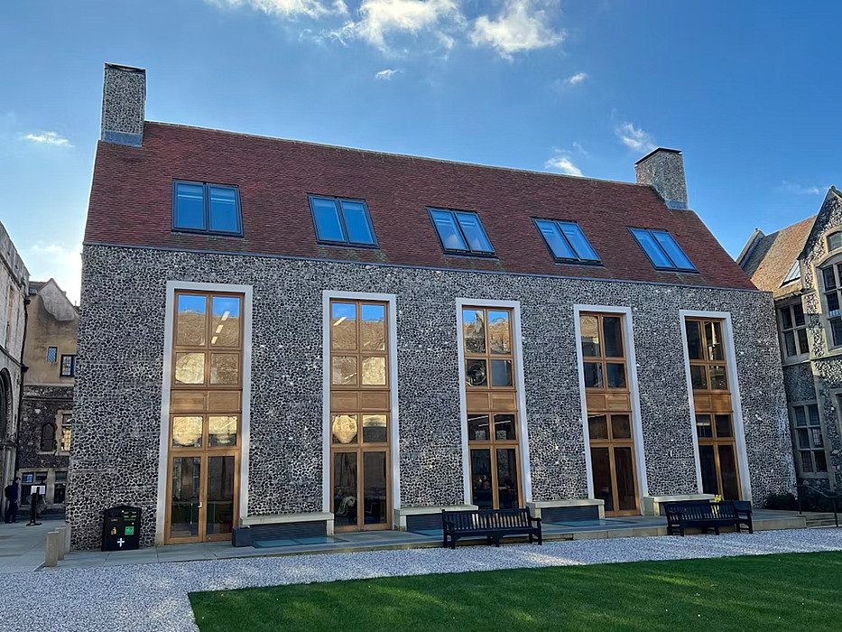 A modern school building with floor-to-ceiling windows which blends in well with the old school buildings