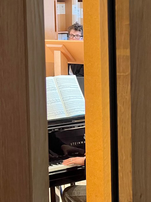 Peak through an open door into the music department where a student is sitting behind a music stand