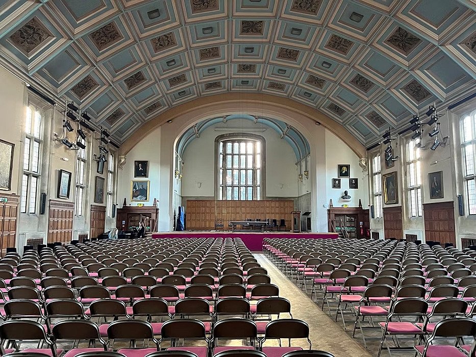 School hall with long rows of chairs in front of a stage at King's School Canterbury